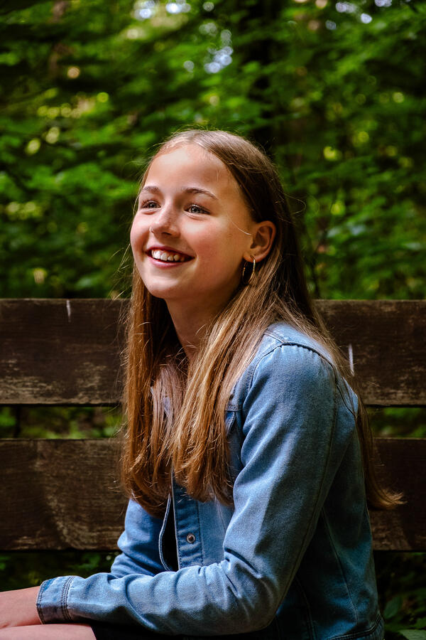 Portrait eines Mädchens mit langen Haaren, lächelnd im Sonnenlicht – natürliche Outdoor-Aufnahme
